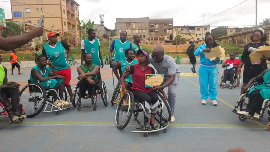 Une joueuse en fauteuil tient fièrement son attestation de participation au camp.