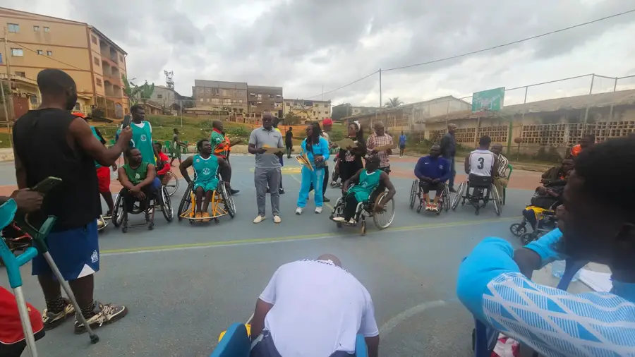 Les joueurs en fauteuil écoutent un encadrant debout au milieu du cercle avant la séance.