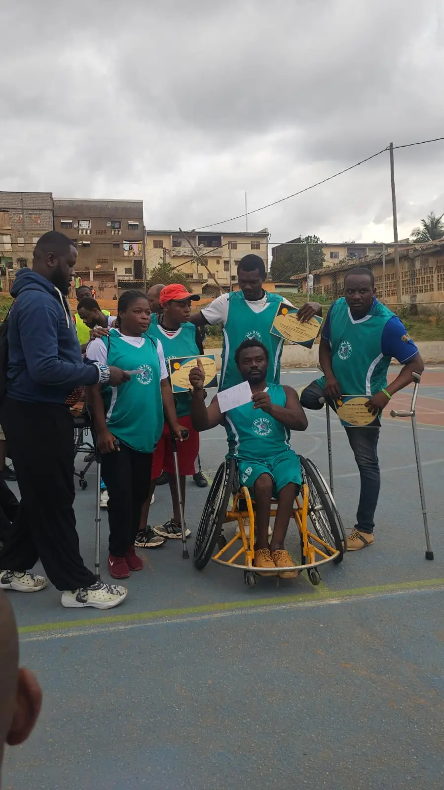 L’équipe en maillots verts pose avec ses attestations, joueurs en fauteuil et sur béquilles.