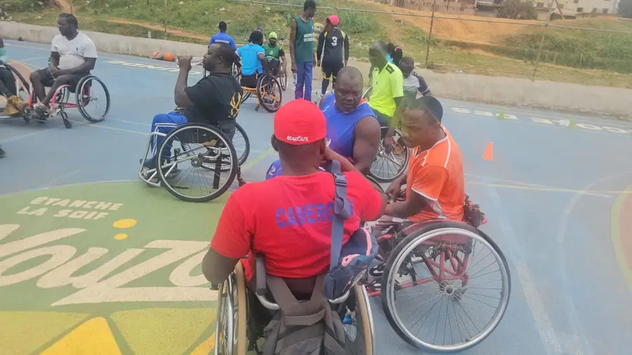 Deux joueurs en fauteuil, casquette rouge et maillot orange, face à face pendant un exercice.