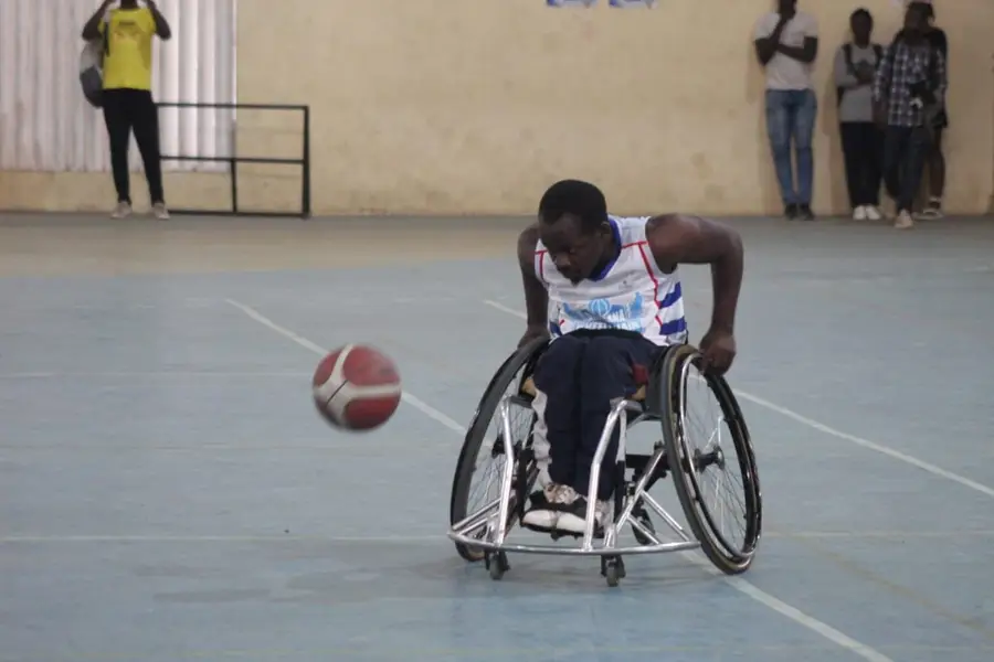 Un joueur pousse son fauteuil derrière le ballon qui rebondit sur le terrain.