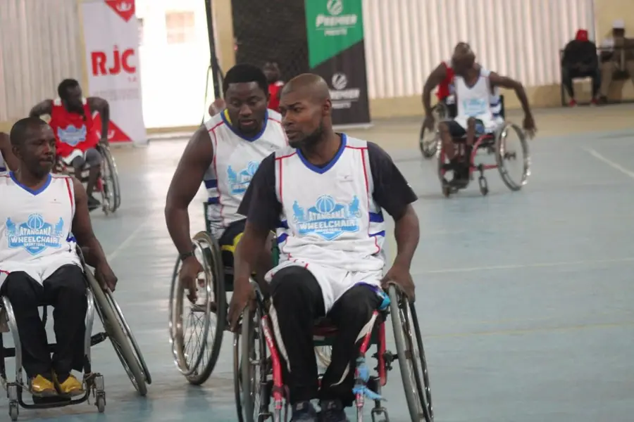 Des joueurs en maillots blancs se déplacent en fauteuil sur le terrain.