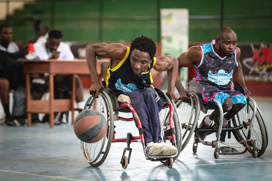 Deux joueurs de basket fauteuil en pleine action, l’un dribble le ballon près du sol.