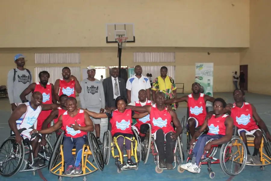 Photo officielle des équipes en fauteuil, maillots rouges et blancs, sous le panier.