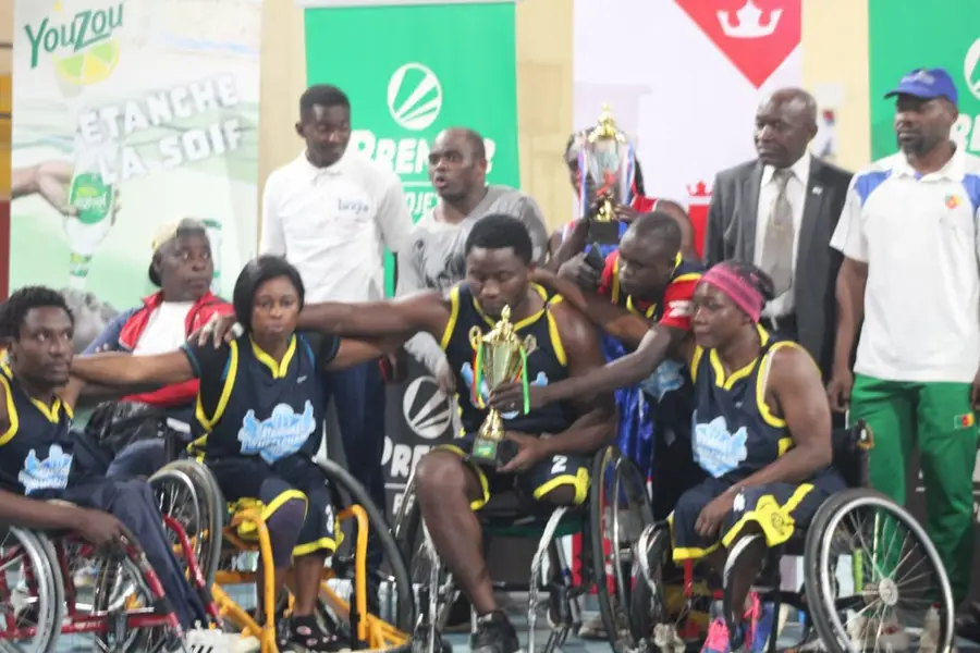 Une équipe en maillots noirs célèbre avec le trophée, entourée d’officiels.